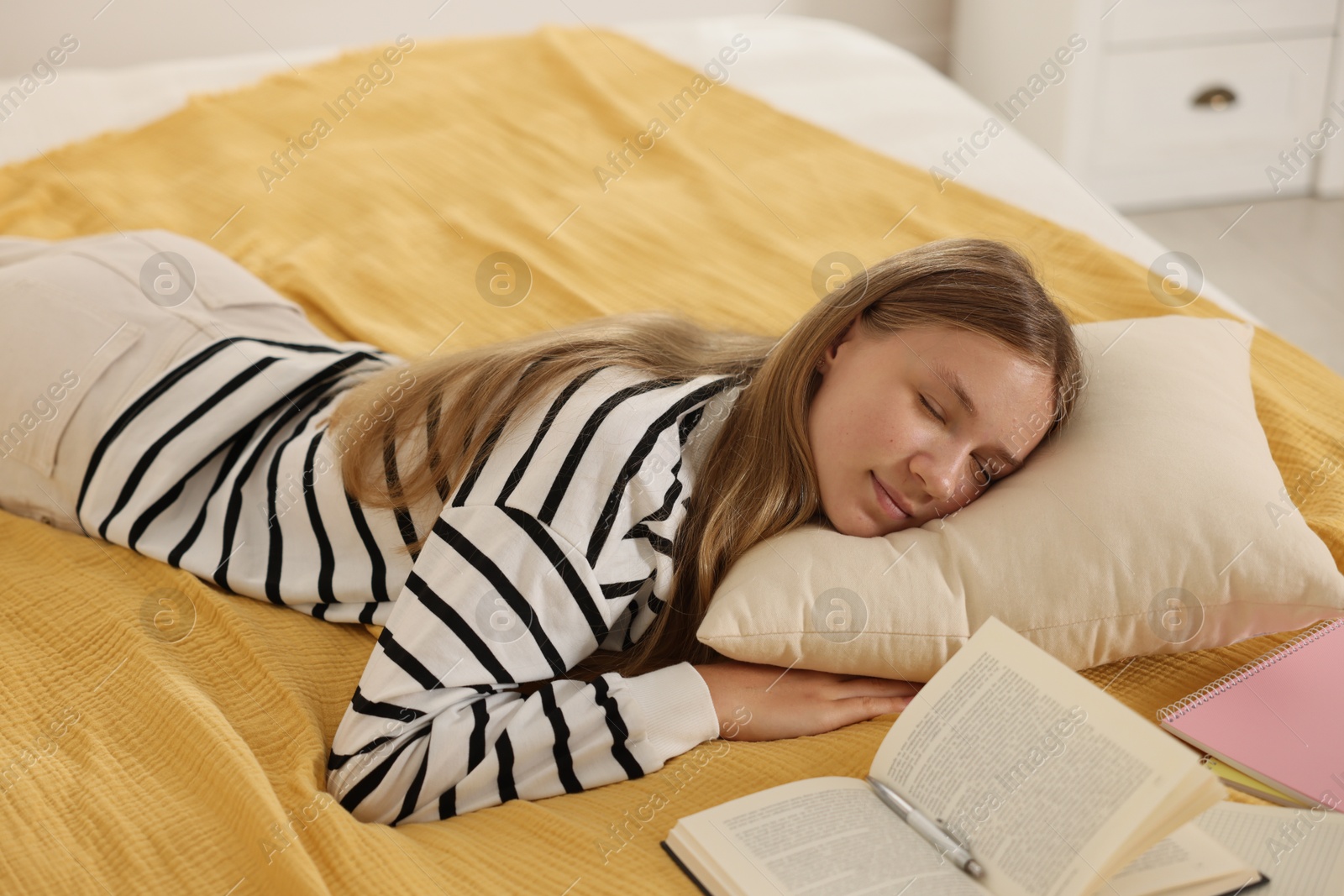 Tired teenage student sleeping near books on bed indoors Photo of Tired teenage student sleeping near books on bed indoors