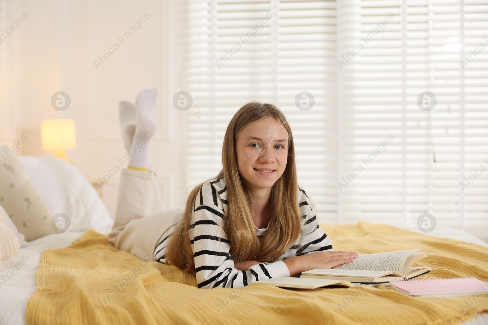 Teenage girl studying with book on bed at home Photo of Teenage girl studying with book on bed at home