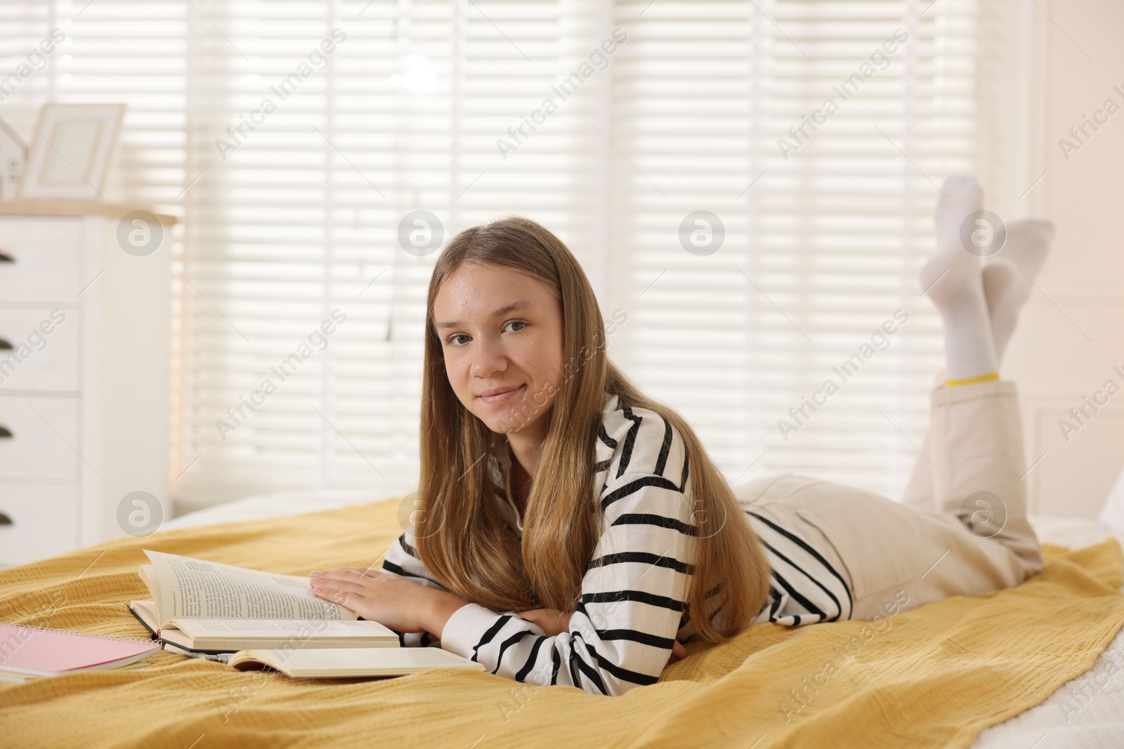 Teenage girl studying with book on bed at home Photo of Teenage girl studying with book on bed at home