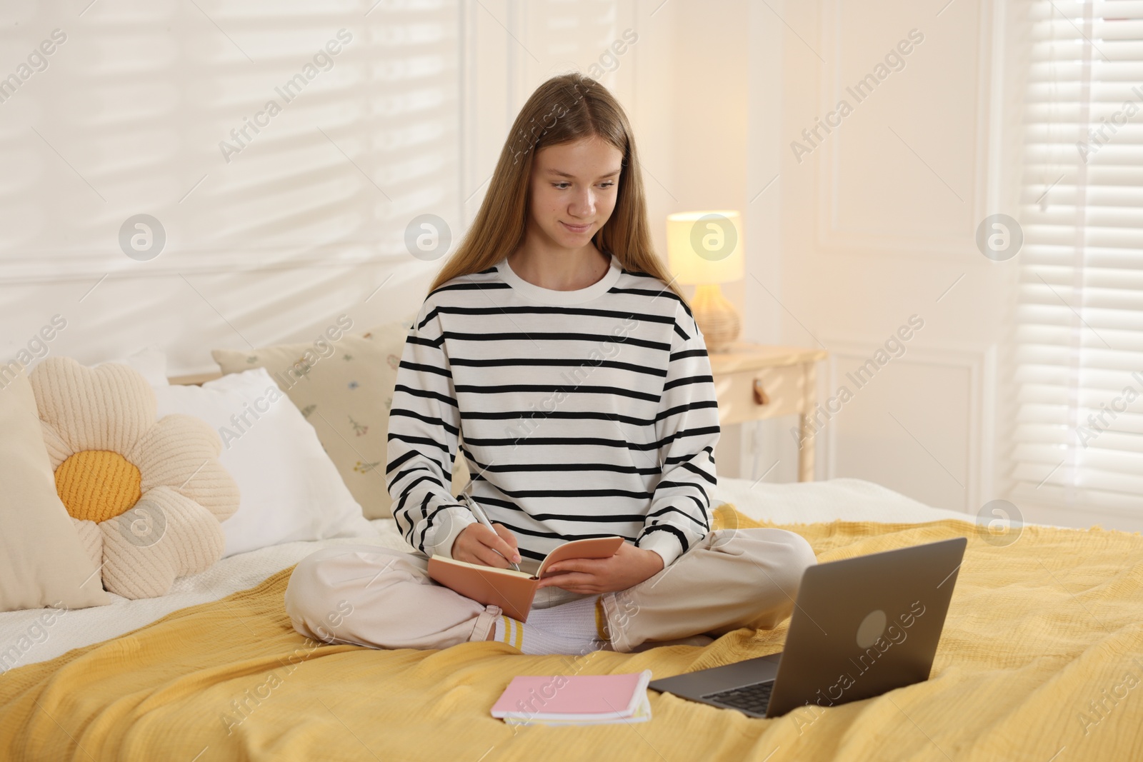 Teenage girl studying online on bed at home Photo of Teenage girl studying online on bed at home