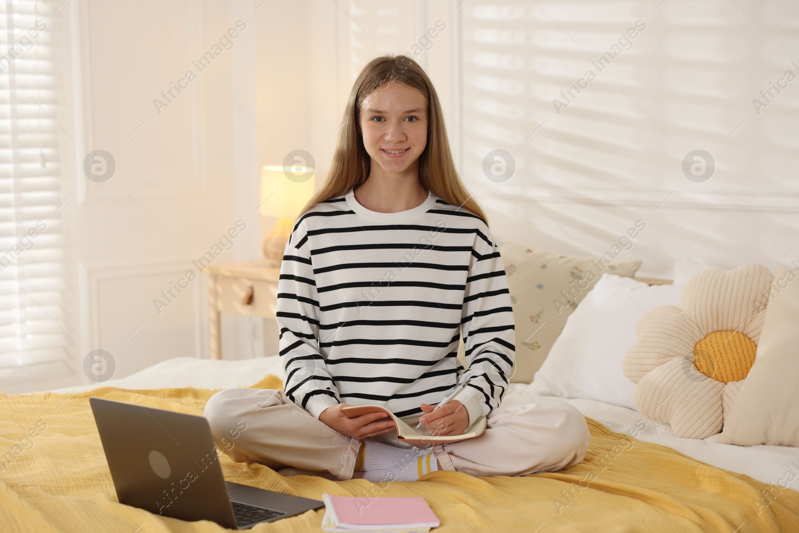 Teenage girl studying online on bed at home Photo of Teenage girl studying online on bed at home