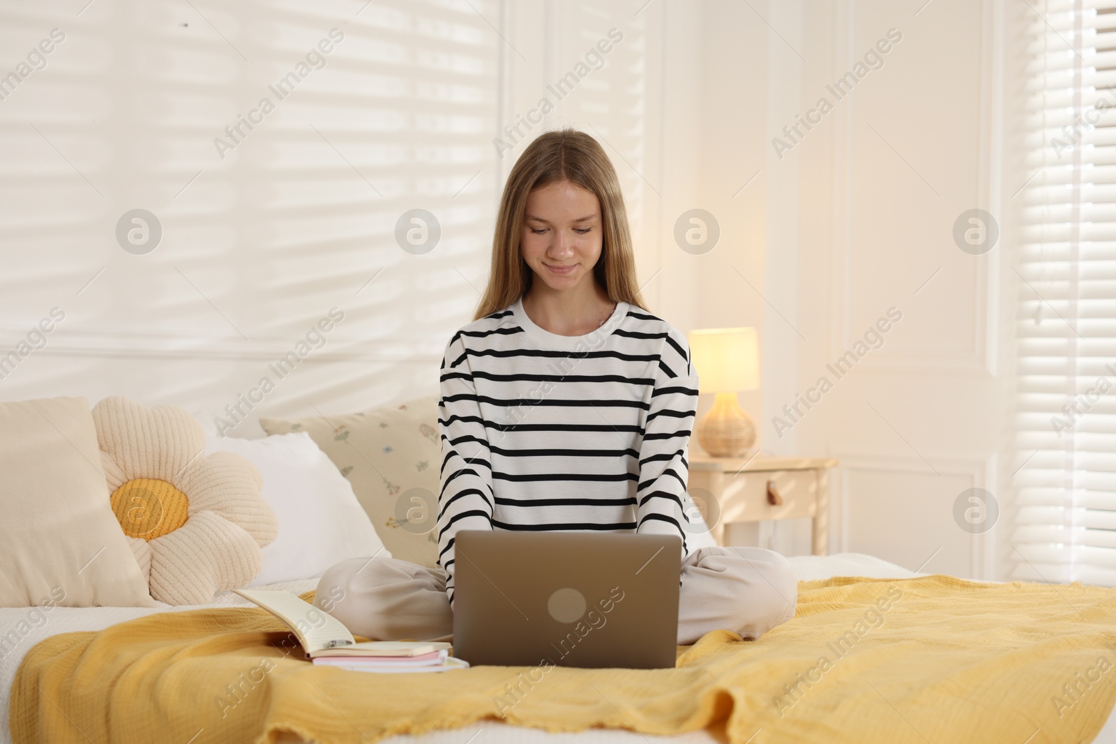 Photo of Teenage girl studying online with laptop on bed at home
