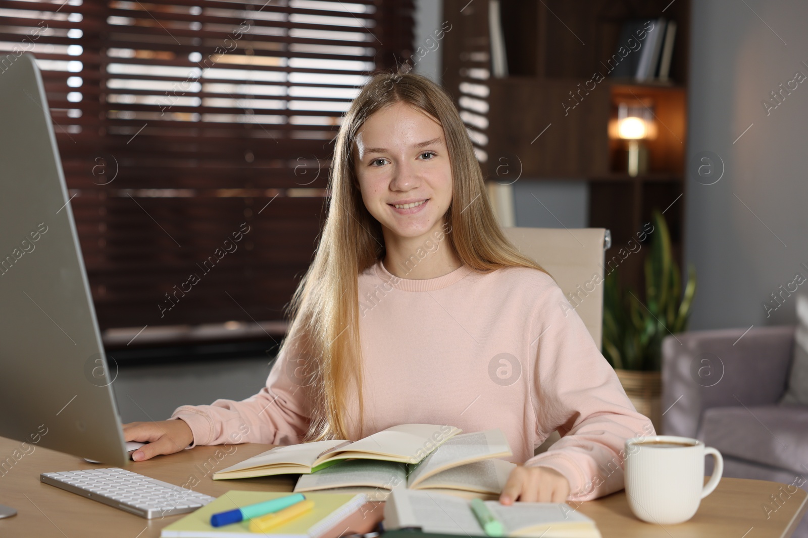 Teenage girl studying online at table indoors Photo of Teenage girl studying online at table indoors
