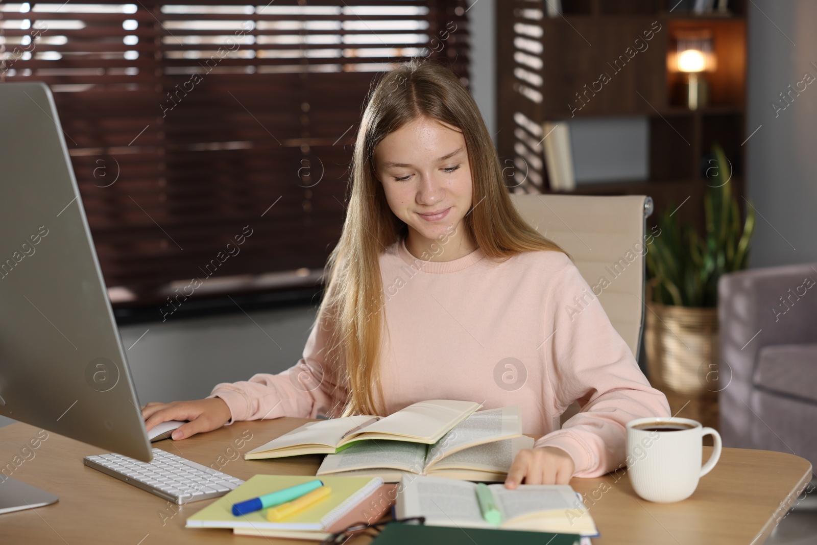 Teenage girl studying online at table indoors Photo of Teenage girl studying online at table indoors