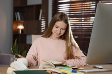 Photo of Teenage girl studying online at table indoors