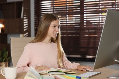 Photo of Teenage girl studying online at table indoors