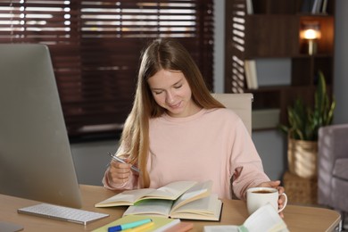 Photo of Teenage girl studying online at table indoors