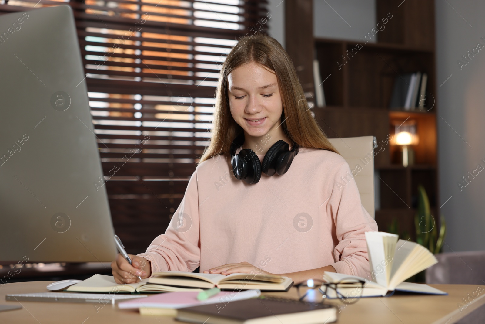 Teenage girl studying online at table indoors Photo of Teenage girl studying online at table indoors