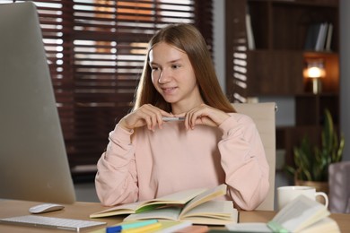 Photo of Teenage girl studying online at table indoors