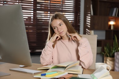 Photo of Teenage girl studying online at table indoors