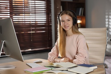 Photo of Teenage girl studying online at table indoors