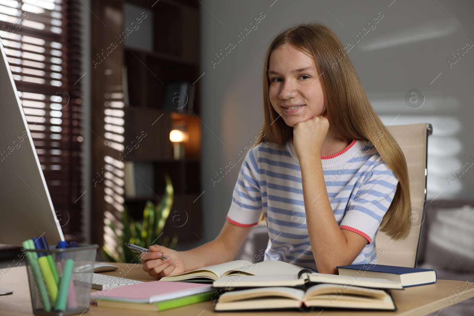 Teenage girl studying online at table indoors Photo of Teenage girl studying online at table indoors