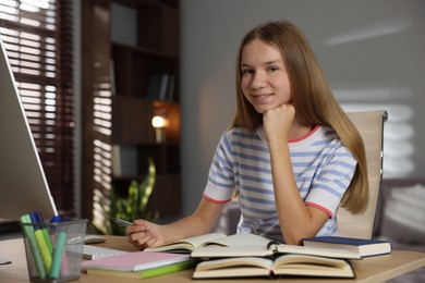 Photo of Teenage girl studying online at table indoors