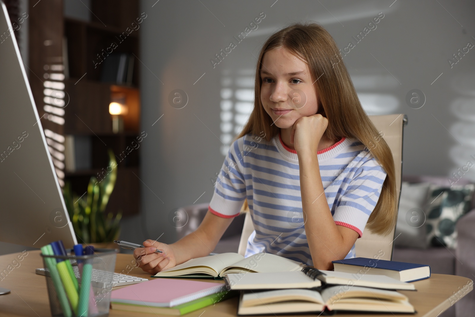 Teenage girl studying online at table indoors Photo of Teenage girl studying online at table indoors