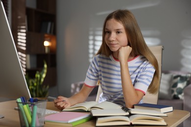 Photo of Teenage girl studying online at table indoors