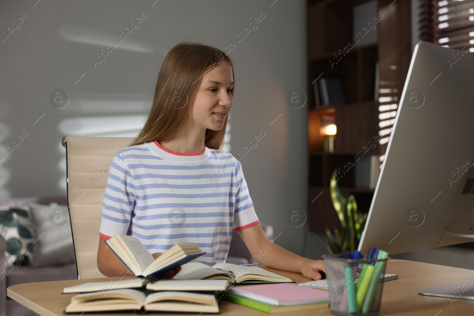 Teenage girl studying online at table indoors Photo of Teenage girl studying online at table indoors
