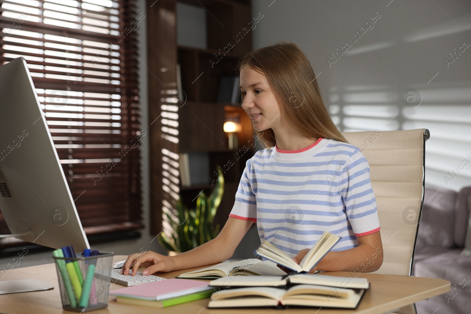 Teenage girl studying online at table indoors Photo of Teenage girl studying online at table indoors
