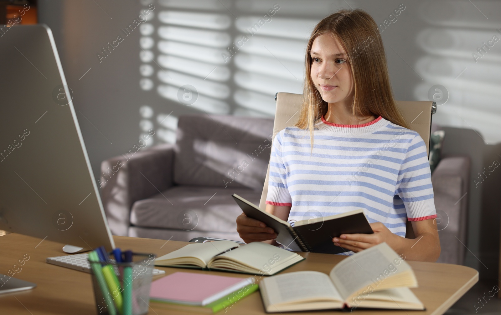 Photo of Teenage girl studying online at table indoors