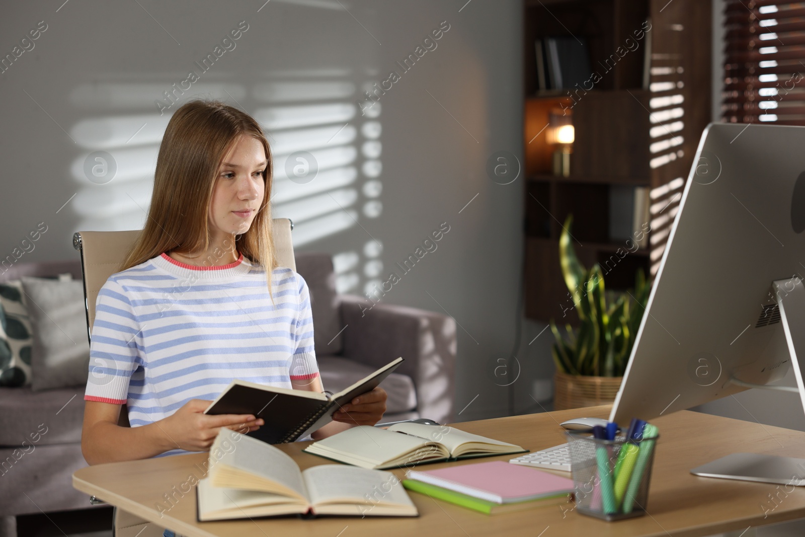 Photo of Teenage girl studying online at table indoors