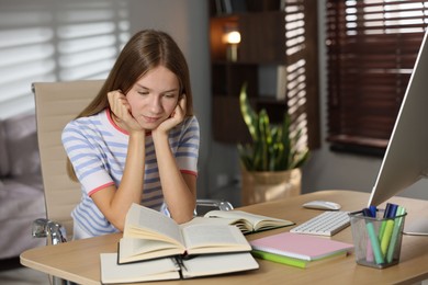 Photo of Teenage girl studying online at table indoors