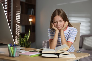 Photo of Teenage girl studying online at table indoors
