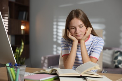 Photo of Teenage girl studying online at table indoors