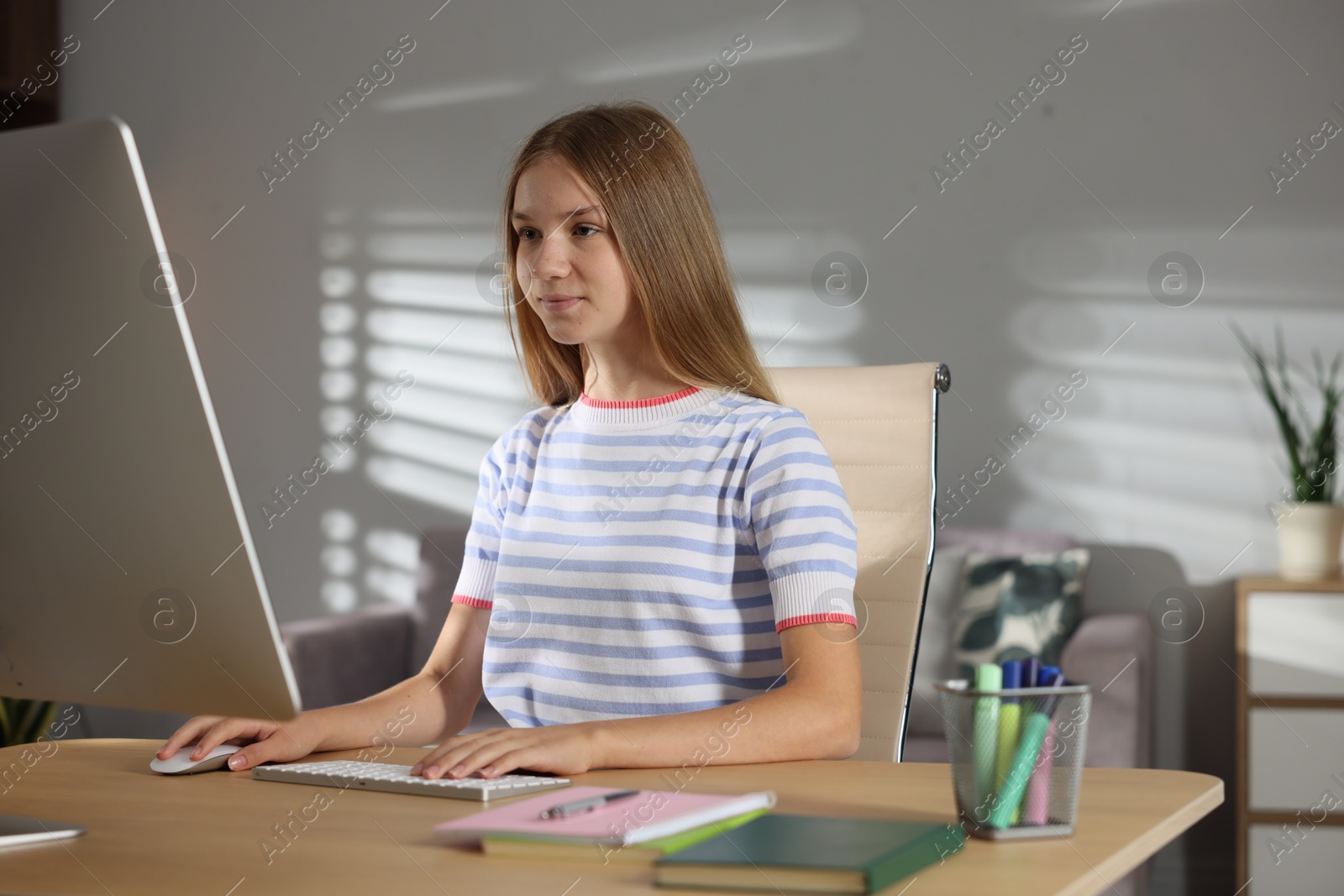 Teenage girl studying online at table indoors Photo of Teenage girl studying online at table indoors