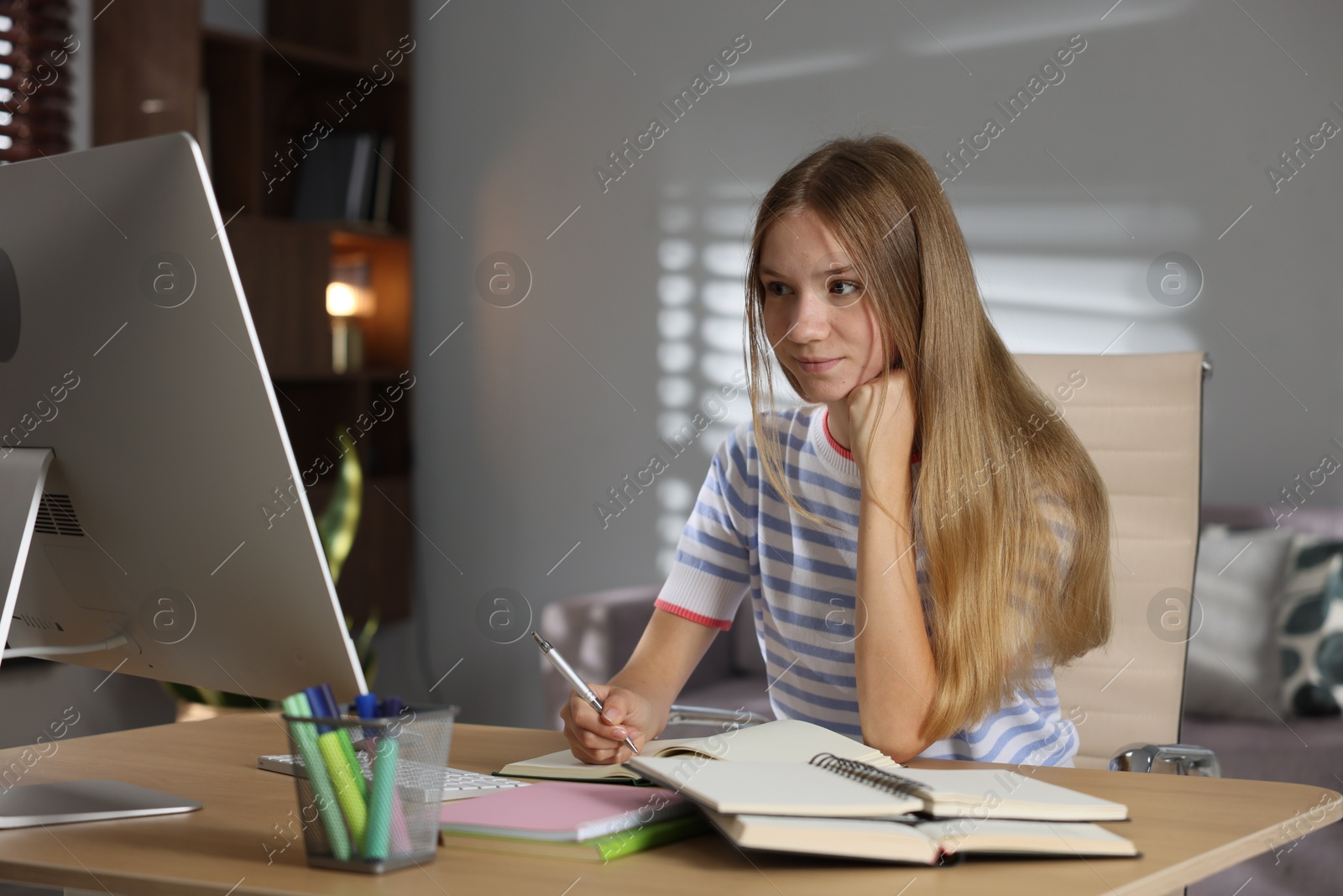 Teenage girl studying online at table indoors Photo of Teenage girl studying online at table indoors
