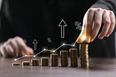 Image of Man stacking coins at table, closeup. Graph with percent signs and arrows above stacks