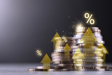 Image of Coins with arrows and percent signs on table against grey background