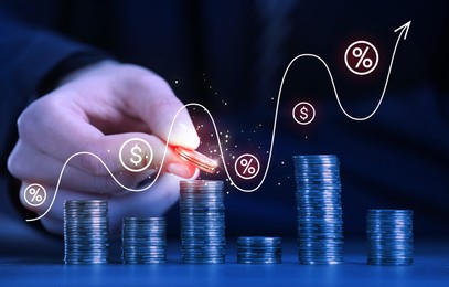 Image of Man stacking coins at table, closeup. Graph with percent and dollar signs above stacks