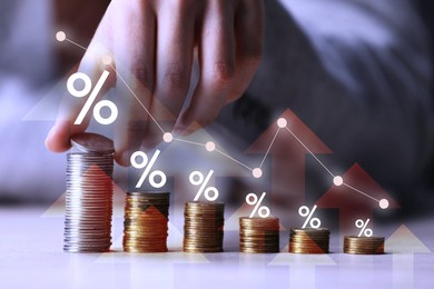 Image of Man stacking coins at table, closeup. Graph with percent signs and arrows above stacks