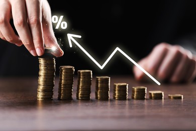 Image of Man stacking coins at table, closeup. Percent sign and arrow above stacks
