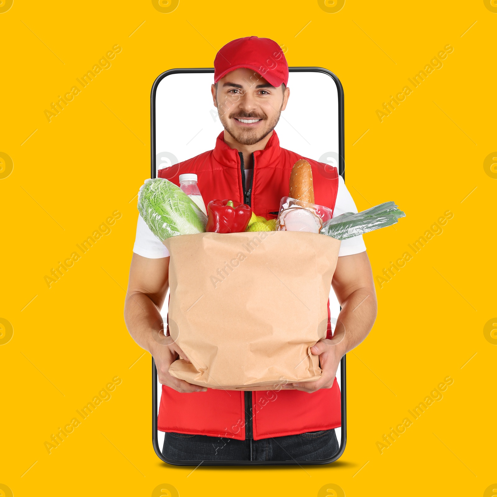 Delivery service worker giving online order out of mobile phone against orange background. Man with paper bag full of food products Image of Delivery service worker giving online order out of mobile phone against orange background. Man with paper bag full of food products