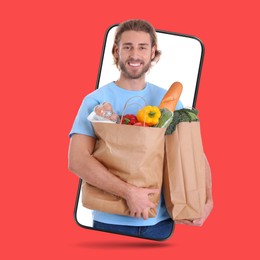 Image of Delivery service worker giving order out of mobile phone against red background. Man with paper bags full of food products