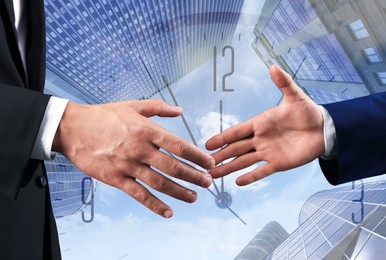 Image of Business people shaking hands, multiple exposure with buildings and clock. Success in partnership, deal, agreement