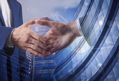 Image of Business people shaking hands, double exposure with buildings. Success in partnership, deal, agreement