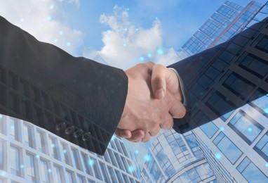 Image of Business people shaking hands, double exposure with buildings. Success in partnership, deal, agreement