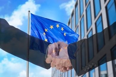 Image of Business people shaking hands, multiple exposure with buildings and flag of European Union. Success in partnership, deal, agreement