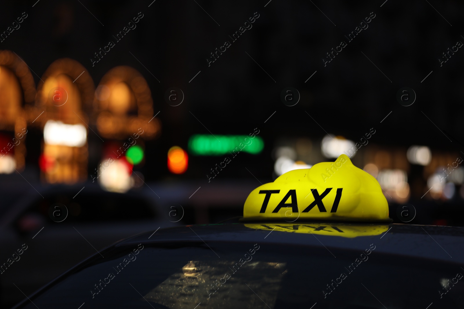 Photo of Taxi car with yellow checkered sign on city street in evening, closeup