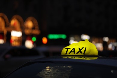 Photo of Taxi car with yellow checkered sign on city street in evening, closeup