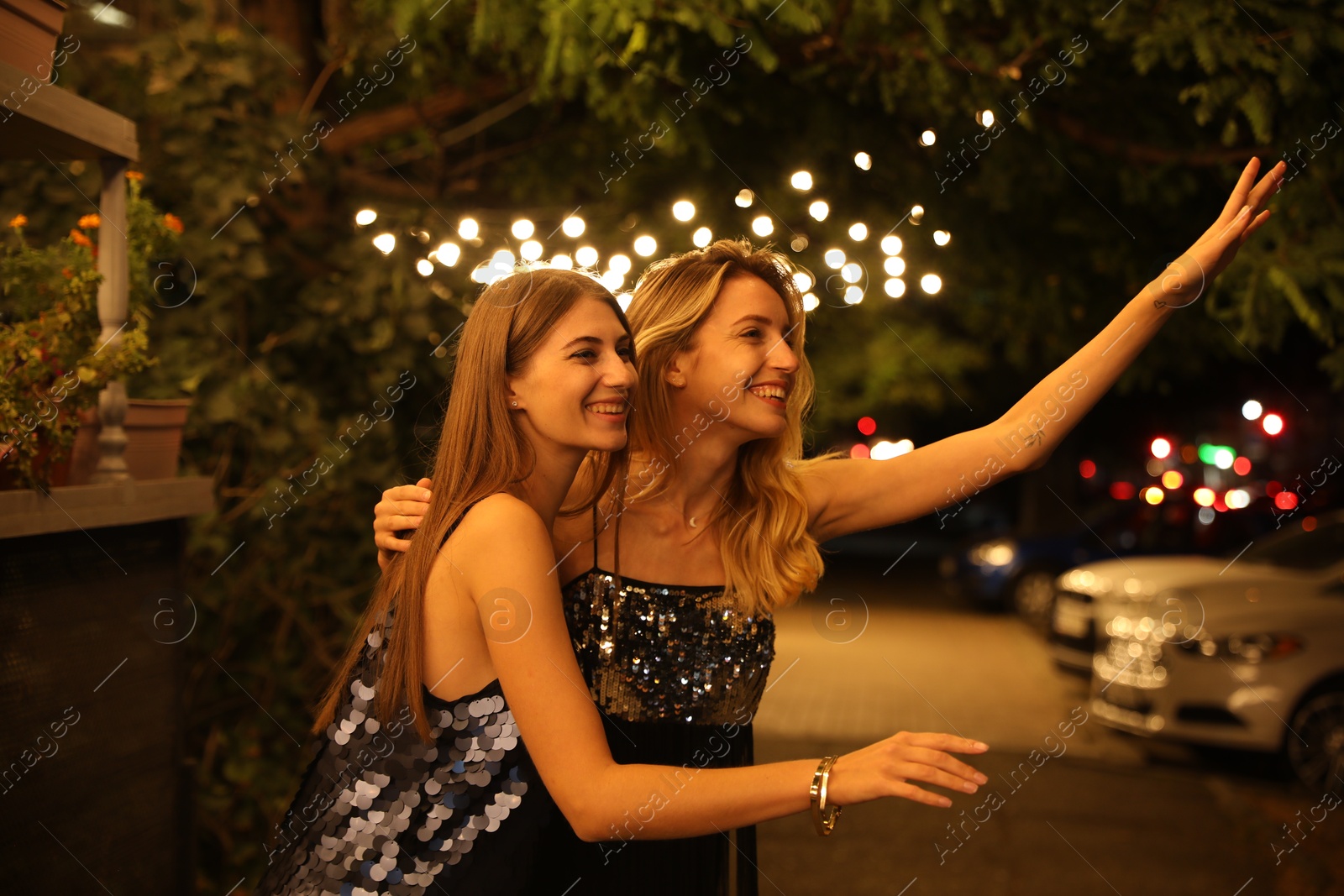 Young women catching taxi on city street at night Photo of Young women catching taxi on city street at night