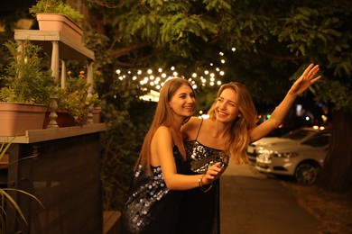 Photo of Young women catching taxi on city street at night