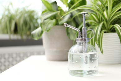 Photo of Spray bottle and different houseplants on white table indoors, closeup. Space for text