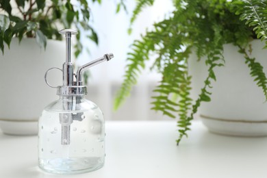 Photo of Spray bottle and different houseplants on white table indoors, closeup. Space for text