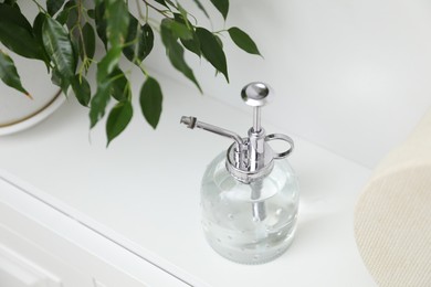 Photo of Spray bottle and potted houseplant on white shelf
