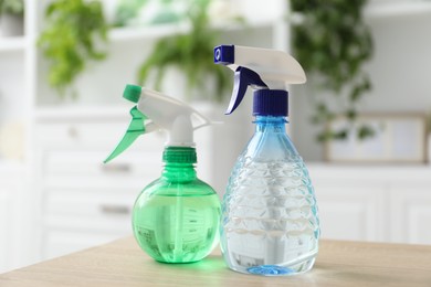 Photo of Houseplant care. Two spray bottles on wooden table, closeup