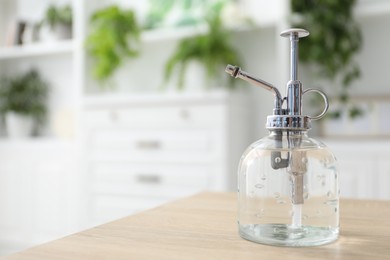 Photo of Houseplant care. Spray bottle on wooden table, closeup. Space for text