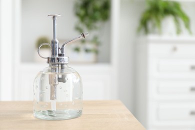 Photo of Houseplant care. Spray bottle on wooden table, closeup. Space for text