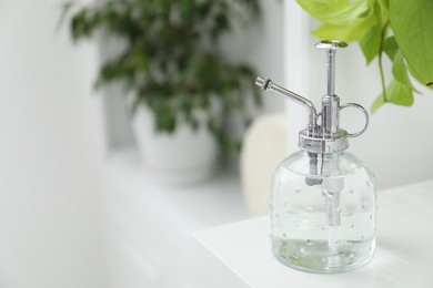 Photo of Spray bottle and potted houseplant on white shelf, closeup. Space for text